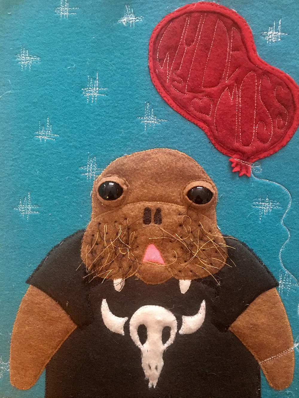 felt portrait of a walrus in a t-shirt with a baloon